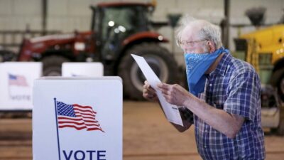 Robert Wilson reviews his selections on his ballot while voting at the town's highway garage building Tuesday, April 7, 2020 in Dunn, Wis. Voters in Wisconsin are waiting in line to cast ballots at polling places for the state's presidential primary election, ignoring a stay-at-home order over the coronavirus threat. (John Hart/Wisconsin State Journal via AP)