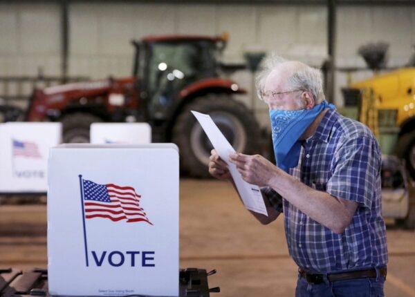 Robert Wilson reviews his selections on his ballot while voting at the town's highway garage building Tuesday, April 7, 2020 in Dunn, Wis. Voters in Wisconsin are waiting in line to cast ballots at polling places for the state's presidential primary election, ignoring a stay-at-home order over the coronavirus threat. (John Hart/Wisconsin State Journal via AP)