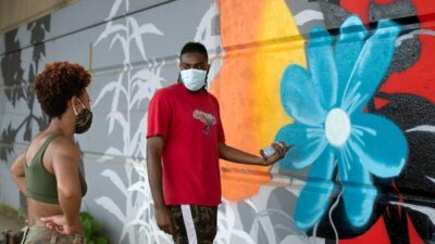 Camerin “Camo” Nesbit gives tips on working with aerosol to fellow muralist Janel Young as they add to a Black Lives Matter mural along the Allegheny River in downtown Pittsburgh. The mural was created by a group of white house painters. (photograph by Martha Rial)