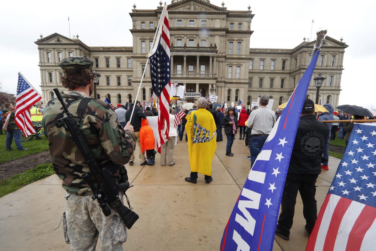 A protester carries his rifle at the State Capitol in Lansing, Mich., Thursday, April 30, 2020. Hoisting American flags and handmade signs, protesters returned to the state Capitol to denounce Gov. Gretchen Whitmer's stay-home order and business restrictions due to COVID-19 while lawmakers met to consider extending her emergency declaration hours before it expires. (AP Photo/Paul Sancya)