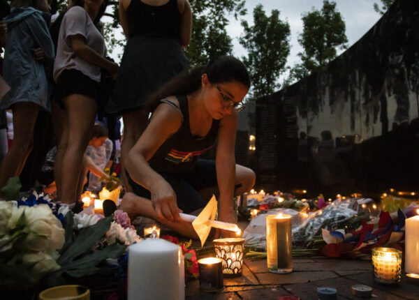 Dozens of mourners gather for a vigil near Central Avenue and St Johns Avenue in downtown Highland Park, one day after a gunman killed at least seven people and wounded dozens more by firing an AR-15-style rifle from a rooftop onto a crowd attending Highland Park's Fourth of July parade, Tuesday, July 5, 2022 in Highland Park, Ill.. (Ashlee Rezin/Chicago Sun-Times via AP)