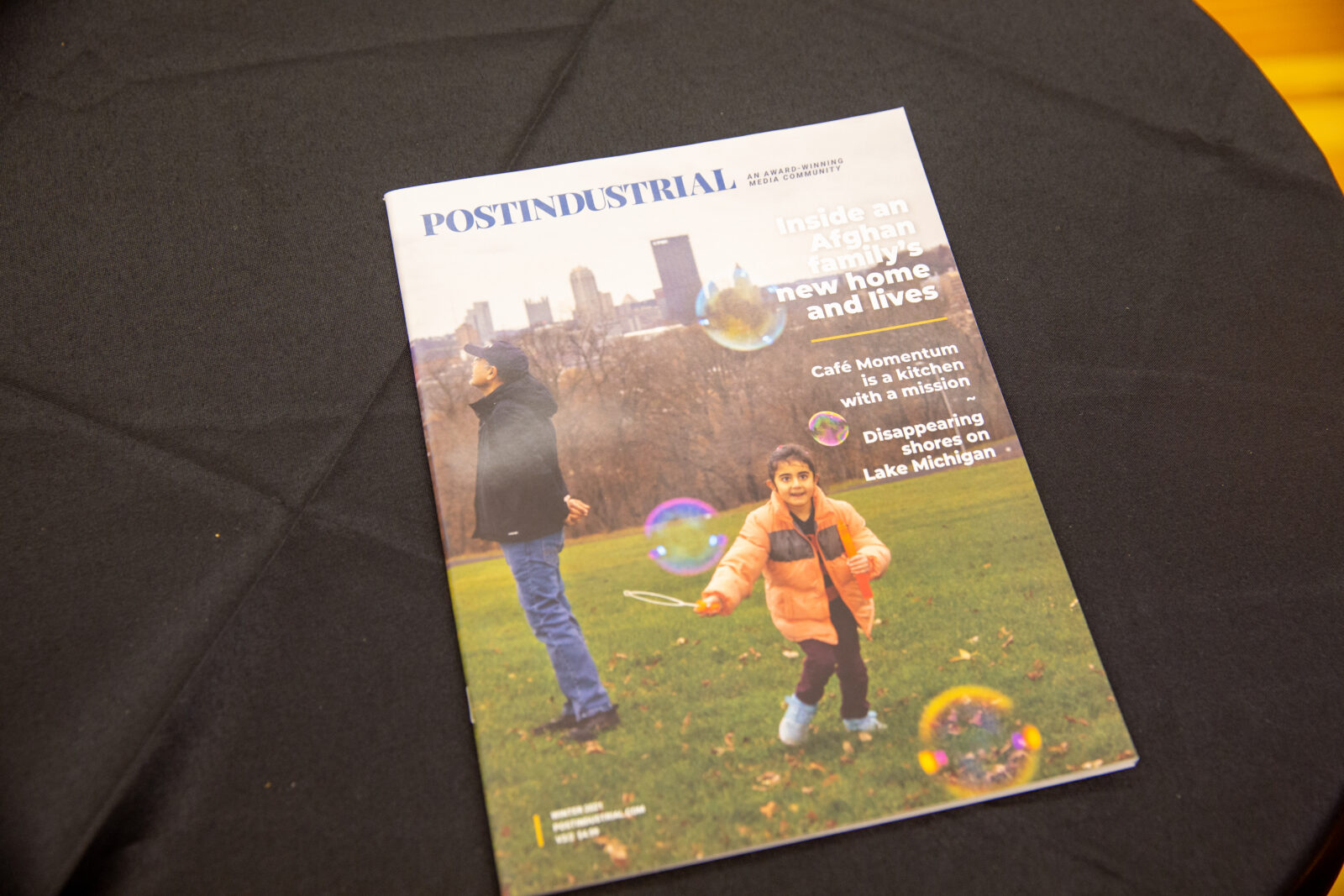 A 2021 edition of Postindustrial Media's magazine. Zubair Babakarkhail's daughter, Javeria Babak, 7, blows bubbles in Pittsburgh's Schenley Park, shortly after they moved here.